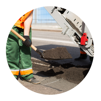 concrete-asphalt-repair-columbus-ohio Worker repairing asphalt pavement by shoveling fresh material onto damaged road surface.