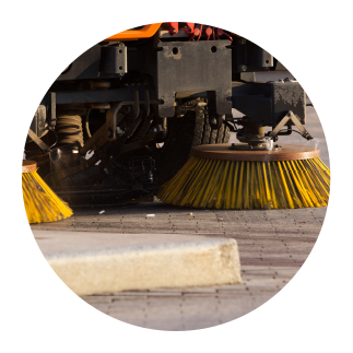 parking-lot-sweeping-maintenance Street sweeping machine cleaning a commercial parking lot with rotating brushes.