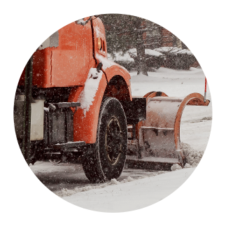 snow-ice-management-plowing Snow plow clearing a roadway during winter storm for safe access.